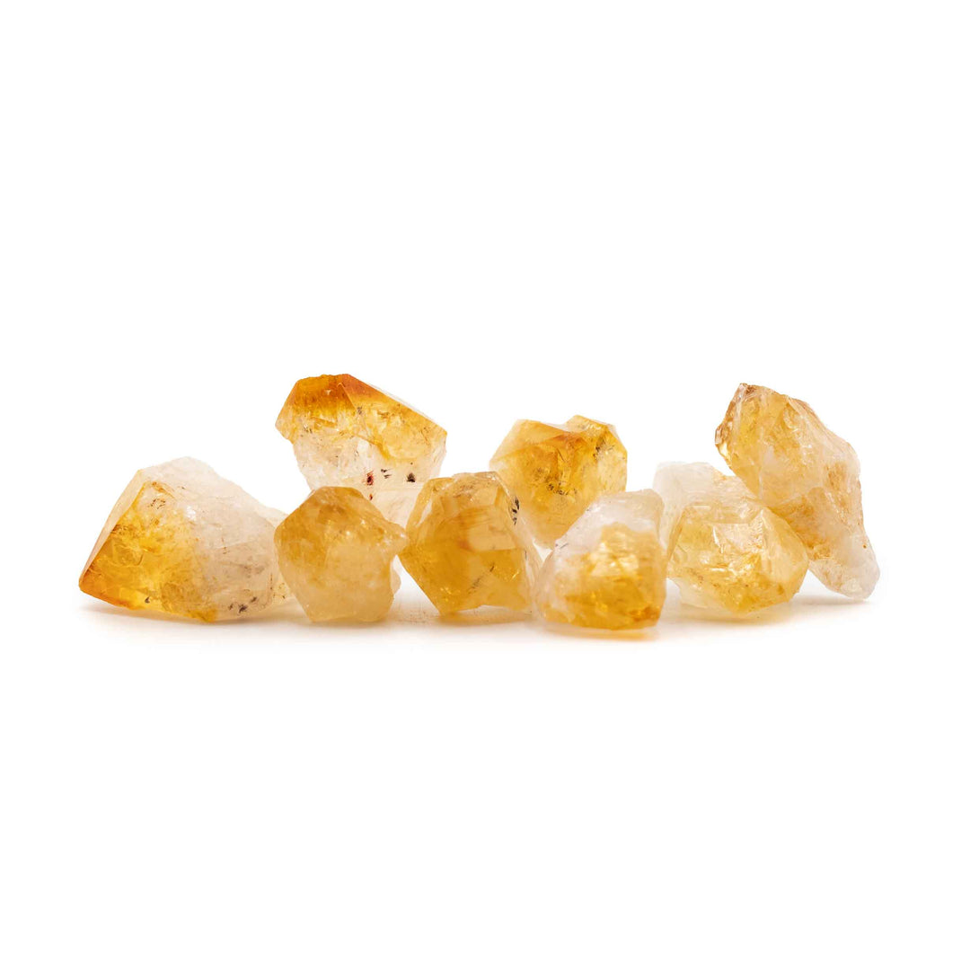Several small, rough heat-treated citrine quartz crystal points arranged horizontally against a plain white background.