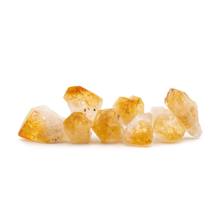 Several small, rough heat-treated citrine quartz crystal points arranged horizontally against a plain white background.