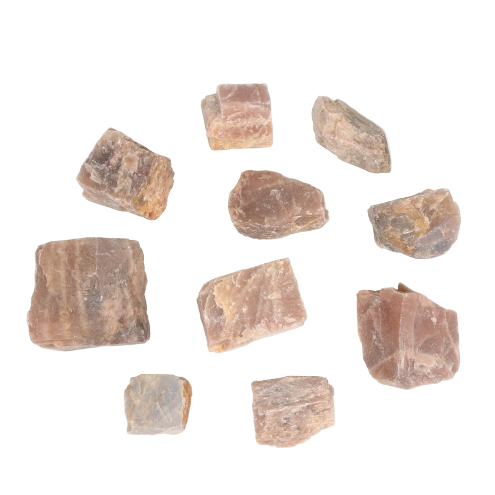 Photograph of multiple rough unpolished feldspar mineral specimens scattered on a white background, featuring varying shades of beige, pinkish-orange, and light brown with visible crystalline structures and striations
